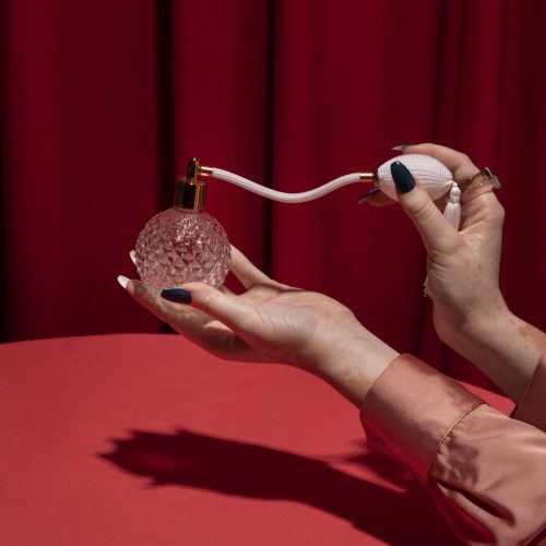 Woman in red holding a vintage perfume bottle