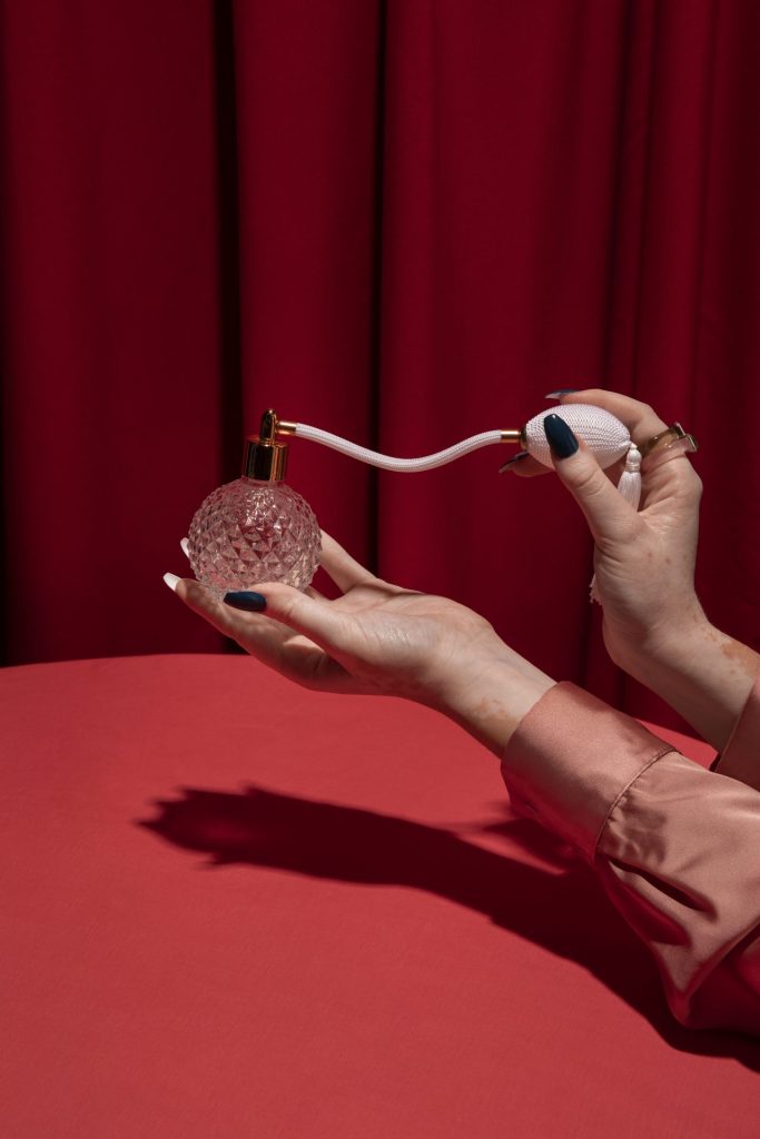 Woman in red holding a vintage perfume bottle