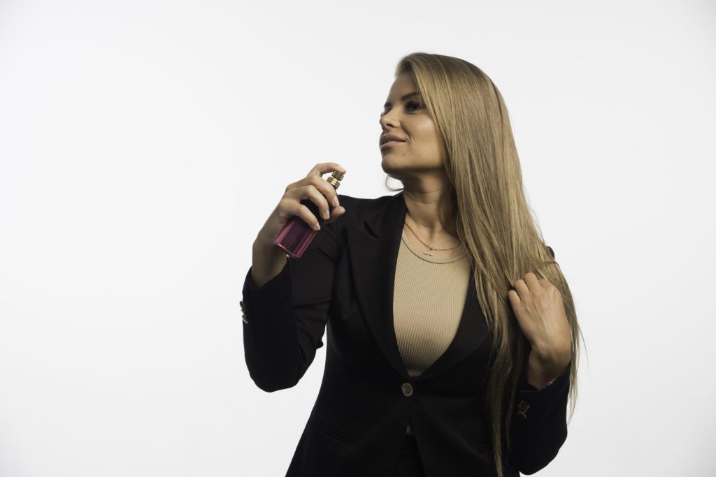 Woman spraying perfume onto clothes